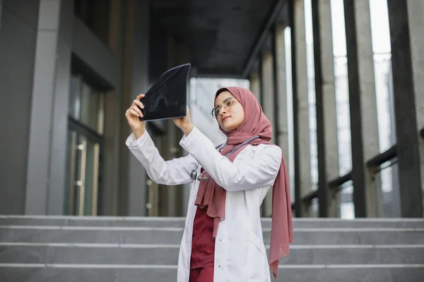 Malaiische Ärztin, die sich Röntgenergebnisse ansieht, steht im Freien — Stockfoto