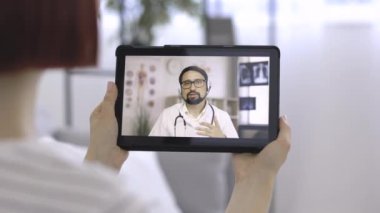 30 yaşında kulaklıklı yakışıklı bir erkek doktor, online danışmanlık yapıyor ve randevu veriyor.