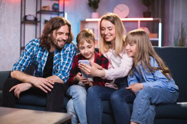 Aile evde komik videolar izlemek için cep telefonunu kullanıyor.