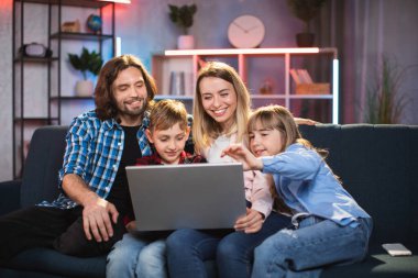 İki çocuklu mutlu ve sevgi dolu bir aile. Evde dizüstü bilgisayardan film izliyorlar.