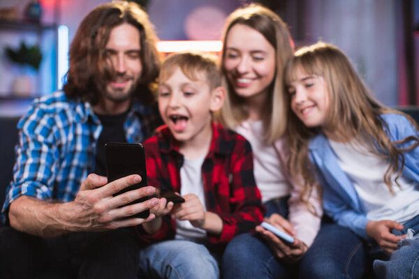 Playful kids and their parents taking selfie on cell phone