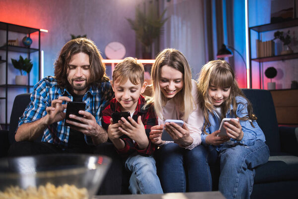 Two kids and their parents using smartphones at home