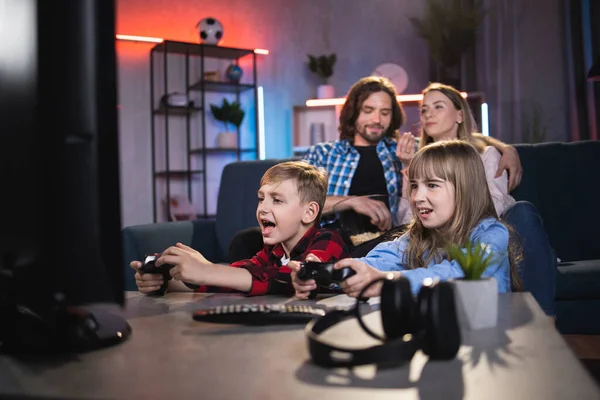 Ouders rusten op de bank terwijl kinderen videospelletjes spelen — Stockfoto