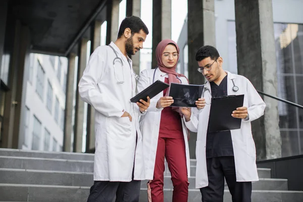 Outdoor shot of team of skilled confident three Asian Indian doctors, looking at patients xray — Stock Photo, Image