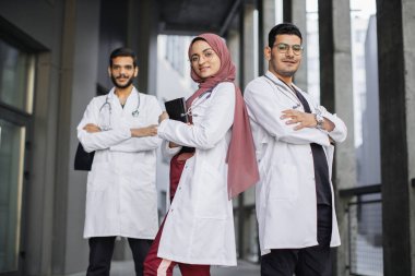 Asyalı Hintli tıp ekibi hastanenin önünde kameraya bakıyor.