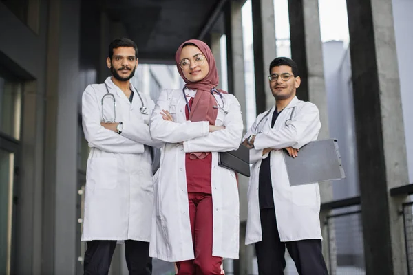 자신감 있는 3 명의 젊은 사우디 아랍 의사들 이 병원 밖에 서서 카메라를 보고 — 스톡 사진