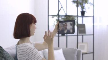 Mutlu 25 yaşında güzel bir kadın tablet bilgisayarın webcam 'inde el sallarken görüntülü arama yapıyor.