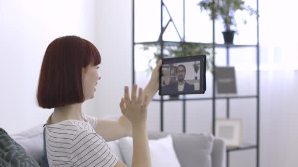 Feliz hermosa mujer de 25 años saludando en la webcam de la tableta, mientras que tener videollamada — Vídeo de stock