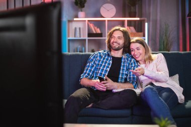 Caucasian couple smiling sincerely while watching TV clipart