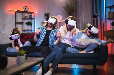VR gözlükleriyle oyun oynayan çocuklu genç ebeveynler.