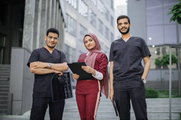 Three doctors, Muslim lady in hijab and two Arabian men, working in front of the clinic — Stock Photo, Image