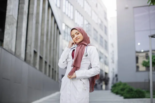 Uśmiechnięta, pewna siebie muzułmanka pielęgniarka lub lekarz, ubrana w hidżab, pozująca przed kamerą na świeżym powietrzu — Zdjęcie stockowe