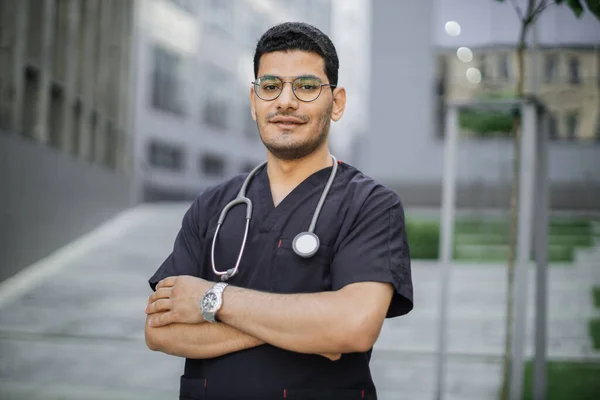 Portrait of young male Asian Arab doctor or student in medical uniform with stethoscope outdoors