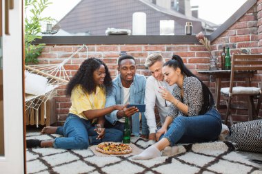 Terasta dinlenirken akıllı telefon kullanan dört arkadaş