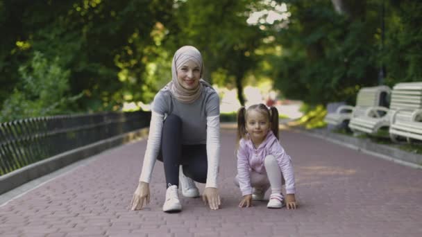 Sporty Arabian mother and her cute daughter on running track getting ready to start run. — Stock Video