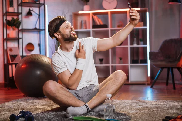 Man with funny face taking selfie on mobile after training