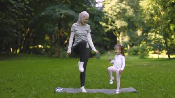 Muslimská matka a její dcera, které mají cvičení v parku, dělá vysoké stepping cvičení — Stock video