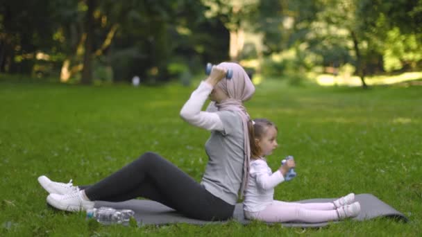 Muselman Arabian kvinna arbetande ute med hantlar tillsammans med hennes dotter i park — Stockvideo