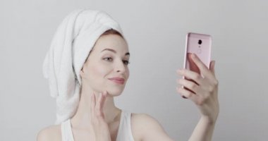 Duştan sonra poz veren, gülümseyen, telefonla video çeken ve yüzlerine dokunan güzel bir manken.