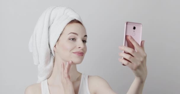 Mooi vrouwelijk model poseren en glimlachen na de douche, schieten video op de telefoon en aanraken gezicht — Stockvideo