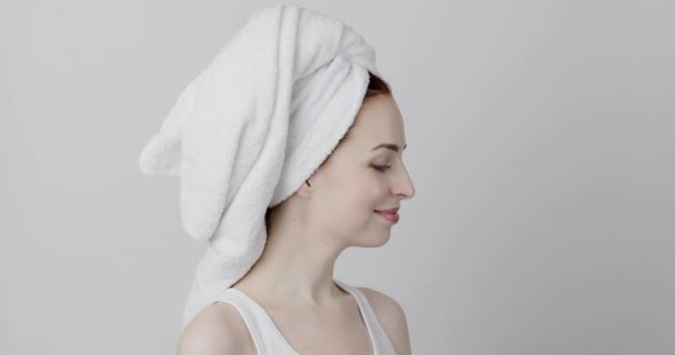 Woman with a towel on head, standing in profile and sending air kiss to the copy space — Stock Video