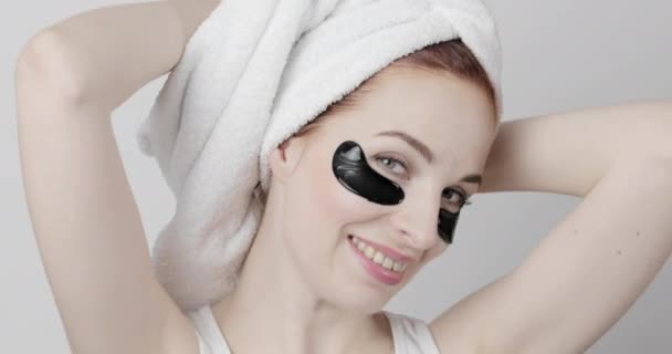 Evropská žena s ručníkem na hlavě a černé pásky přes oko šťastně se usmívá a tančí na kameře — Stock video