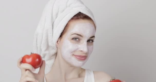 Jonge vrouw met biologische crème masker op gezicht, plezier hebben en dansen op de camera met twee tomaten — Stockvideo