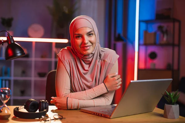 Kellemes mosoly 30 éves arab muszlim nő fejkendőben, ül az asztalnál laptoppal — Stock Fotó