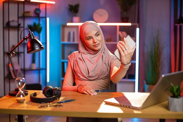 Muszlim arab hölgy fejkendőben, otthon ül a munkahelyén, és telefonos szelfit készít. — Stock Fotó