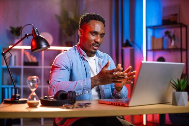 Video konferansı için dizüstü bilgisayar kullanan yakışıklı bir zenci.