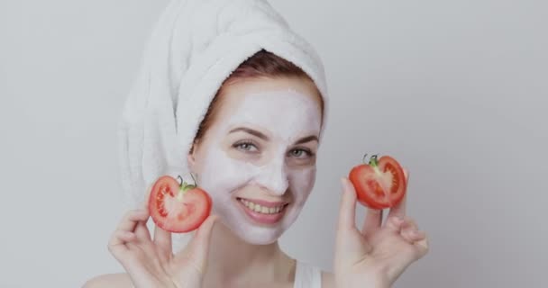 Mladá dáma s obličejovou maskou s rajčatovým extraktem, drží dvě poloviny čerstvého rajčete — Stock video
