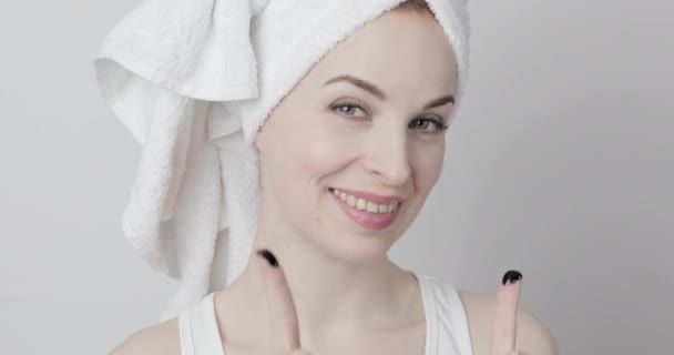 Preciosa mujer con toalla en la cabeza, aplicando mascarilla de carbón negro purificante en su cara — Vídeo de stock