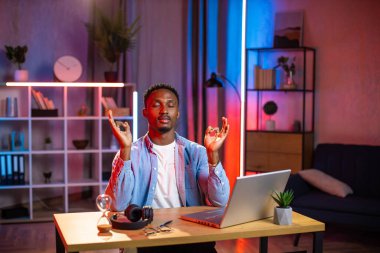 Afrikalı adam evdeki masada oturuyor ve Mudra zen 'de gözleri kapalı meditasyon yapıyor.