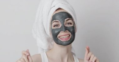Kafasında havlu olan güzel bir kadın çamur maskesi kuruyana kadar dans ediyor..