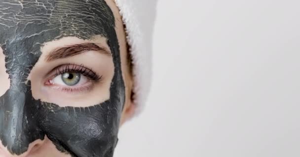 Красивая молодая женщина с высушенной глиняной грязью детоксикации черная маска на лице, глядя в камеру — стоковое видео