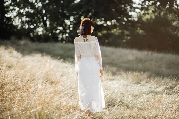 Tribal calma nativa americana mulher em vestido branco, de pé no fundo do pôr do sol no campo selvagem — Fotografia de Stock