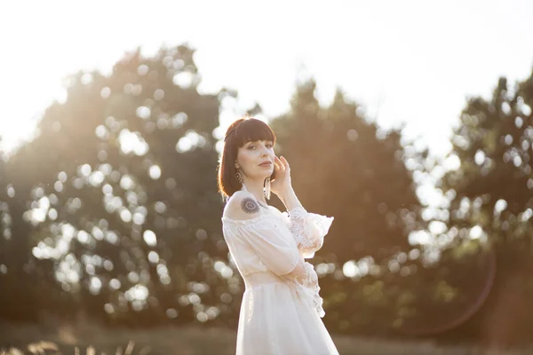 Femme avec des tatouages, habillée dans le style amérindien, posant à la caméra en plein air dans le champ d'été — Photo