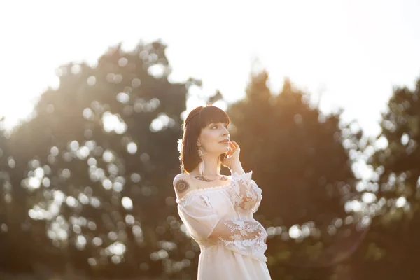 Mulher nativa americana, vestindo vestido boho, acessórios de penas, olhando para o campo de verão — Fotografia de Stock