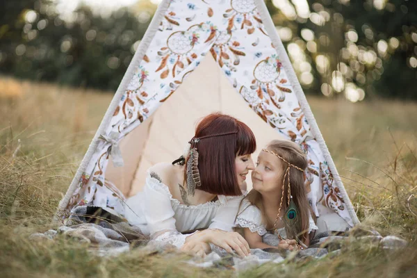 Jolie mère et mignonne petite fille, toucher le nez et câliner tout en étant couché dans wigwam dans le champ — Photo