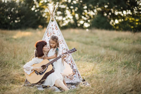 Mère souriante enseigne à sa petite fille comment jouer de la guitare, passer du temps libre à l'extérieur — Photo