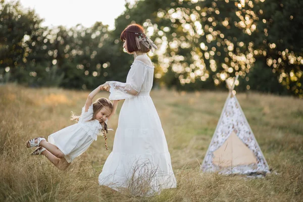 Bela mãe boho gira sua filha bonita. tenda teepee no fundo — Fotografia de Stock