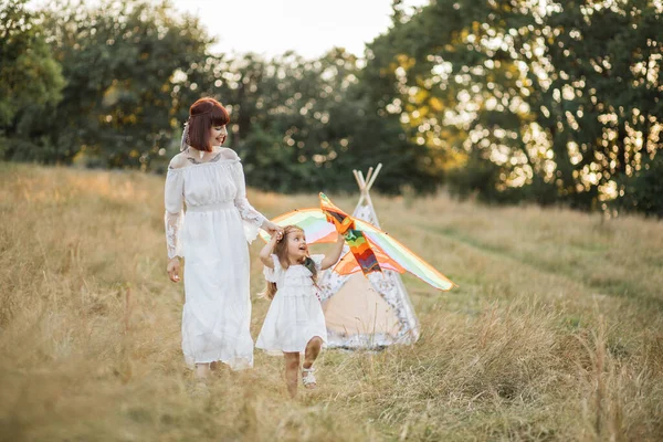 かわいいです女の子ランとともにAカイトでザ夏フィールドで日没時,手の彼女の母親 — ストック写真