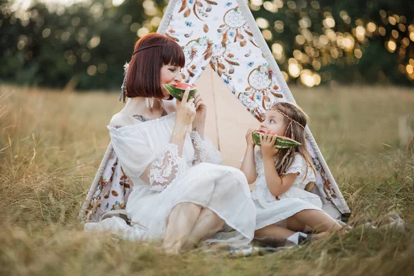 Boho hippie mãe e filha fazendo piquenique no campo de verão, e comer melancia — Fotografia de Stock