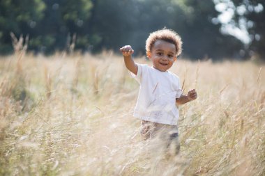 Otların arasında dikilen Afrikalı bir çocuğun portresi.