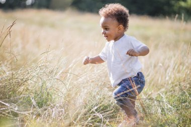 Neşeli Afrikalı çocuk otların arasında eğleniyor.