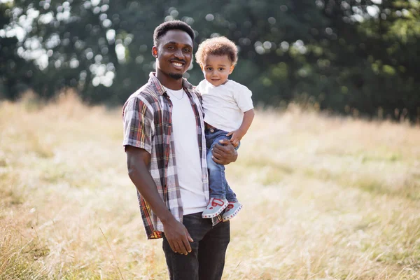 Hombre africano posando con su hijo pequeño en el campo de verano — Foto de Stock