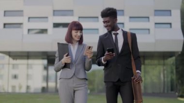 Güzel beyaz kadın ve resmi olarak Afrikalı Amerikalı erkek açık havada telefon kullanıyorlar.