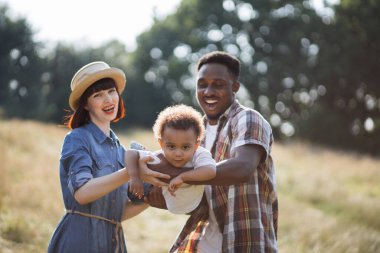Mutlu anne babalar temiz havada sevgili oğluyla oynuyorlar.