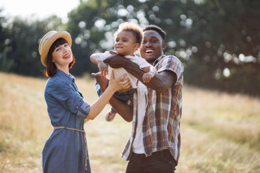 Afrikalı baba ve beyaz anne oğluyla sahada oynuyorlar.