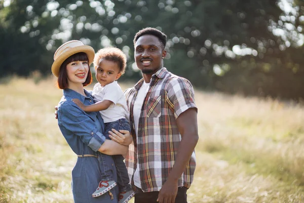 Adorables padres multirraciales posando con un lindo hijo en el campo — Foto de Stock